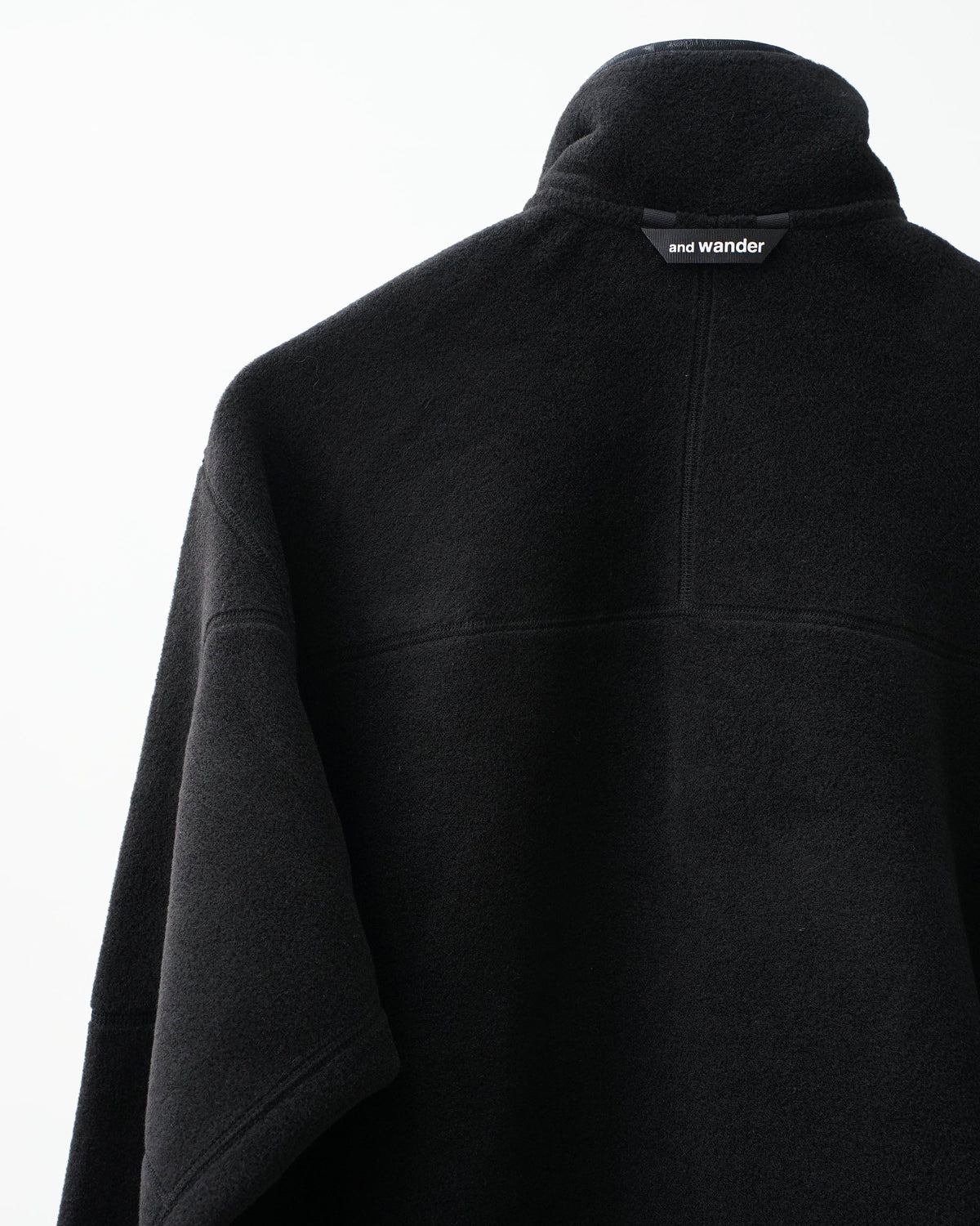 and wander wool fleece pullover (black)。襟元のブランドタグ。