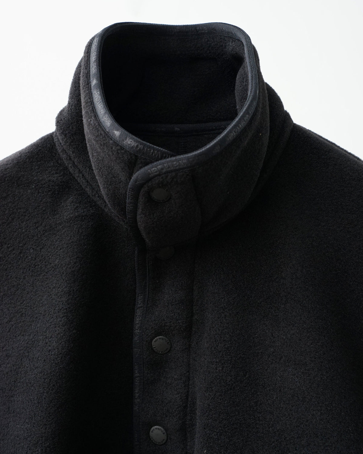 and wander wool fleece pullover (black)。襟元のデザインとスナップボタンのアップ。