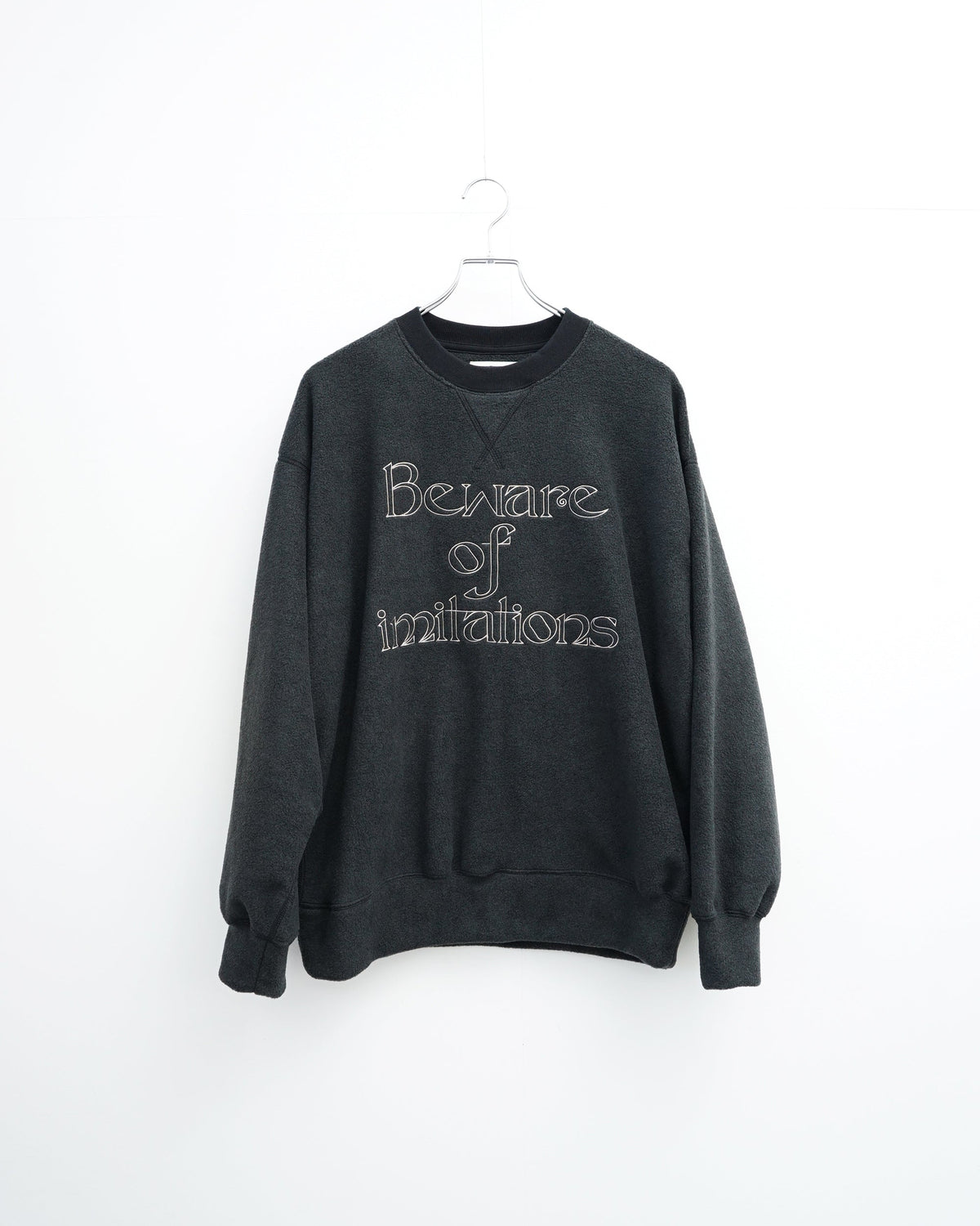 O-の刺繍入りクルーネックスエット。フリース素材のブラック。正面から見た全体像。