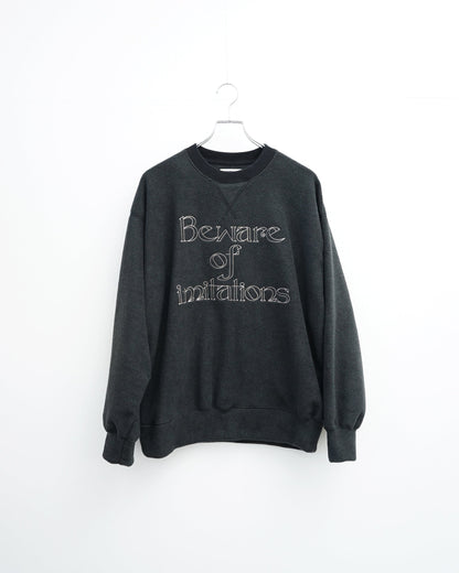 O-の刺繍入りクルーネックスエット。フリース素材のブラック。正面から見た全体像。