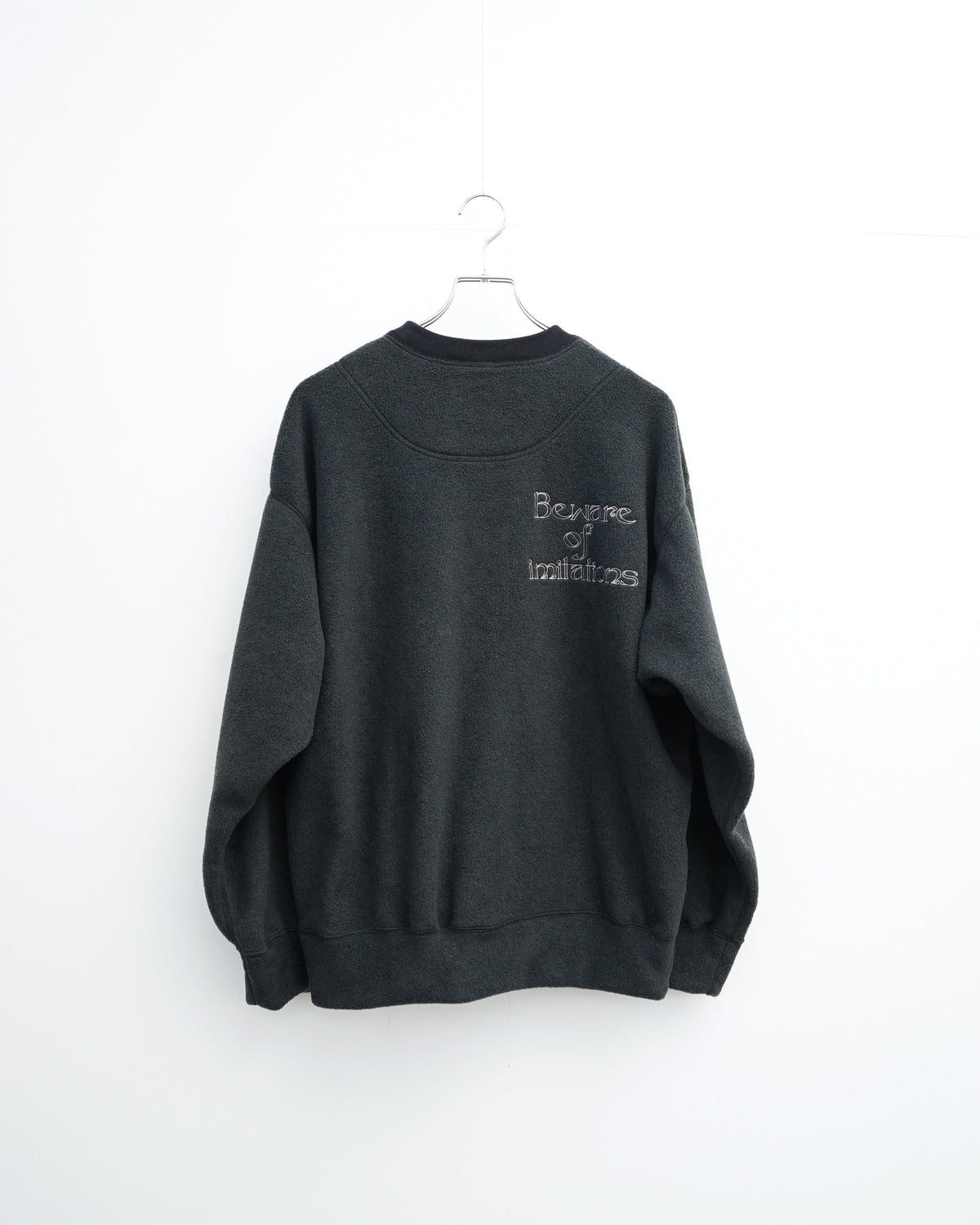 O-の刺繍入りクルーネックスエット。フリース素材のブラック。背面から見た全体像。